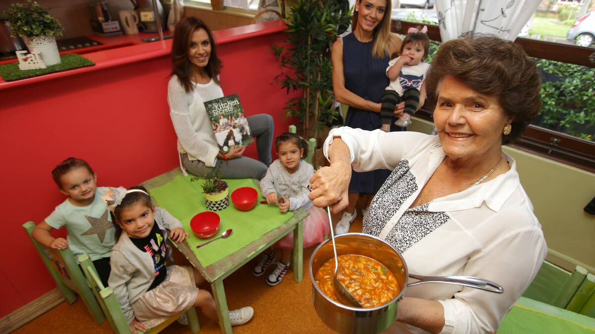 Old-fashioned cooking: Mary Mitropolous who cooks at the Little Darlings Child Care Centre has published a family cookbook. Photo of her cooking with daughters Poppy (right) and Mirika, holding Mia, with children Malena, Christina and Olympia. Picture: John Veage
