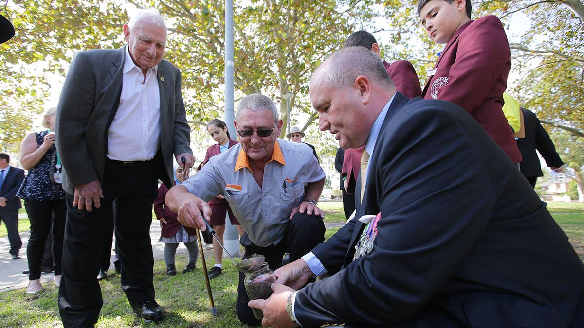 Veterans Affairs Minister David Elliott (right) collects soil from the Arncliffe memorial watched by members of the Arncliffe RSL Sub-branch. Photos: John Veage
