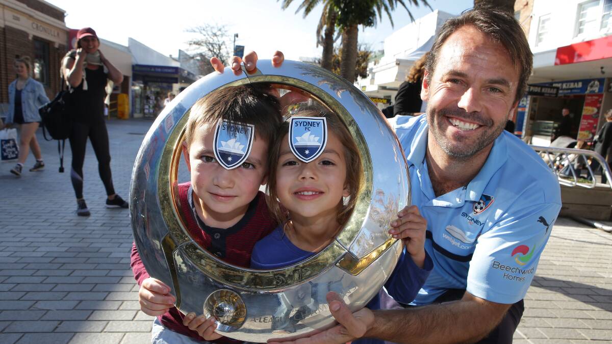 Sky Blues in the shire: Sydney FC community football officer Paul Reid with young fans Eli and Avery as well as the A-League trophy in Cronulla Mall on Wednesday. Picture: John Veage