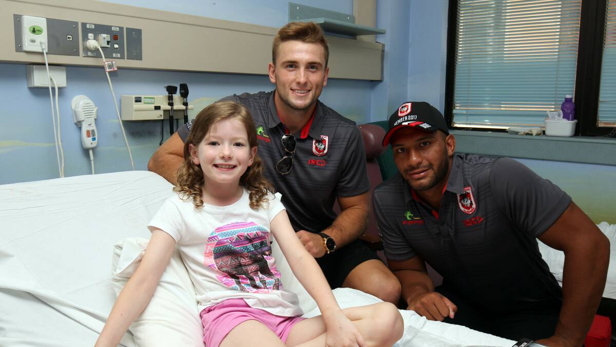 Smiling faces: St George Illawarra Dragons players Jacob Host (centre) and Taane Milne paid a visit to St George Hospital last week to see patients in the children's ward, including Charlotte Fradd. Picture: Chris Lane