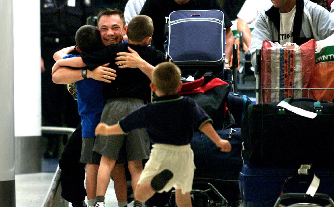 Into his arms: Kostya Tszyu with his son Tim (left), nephew (right) and son Nikita (running) at Sydney International Airport after returning from his victory over American Zab Judah. Picture: Craig Golding
