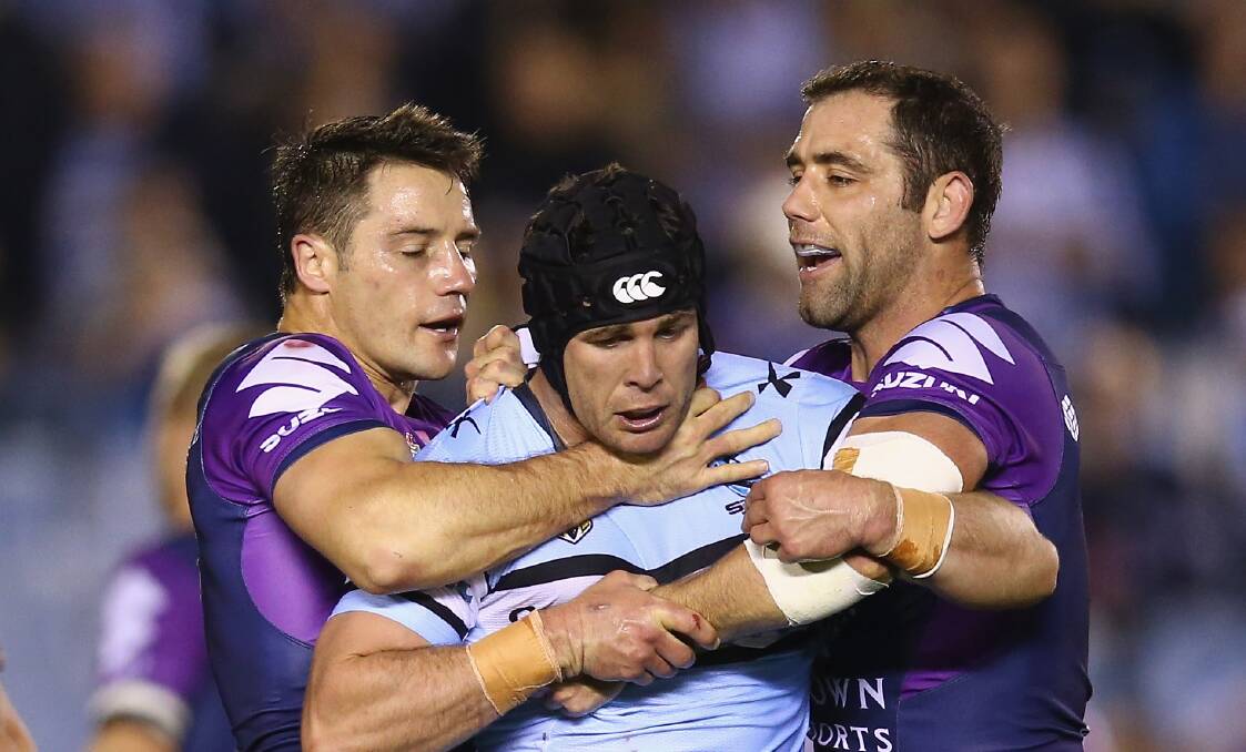 Rivals: Melbourne captain Cameron Smith [right] and halfback Cooper Cronk [left] surround Cronulla hooker Michael Ennis. Picture: Mark Kolbe/Getty Images