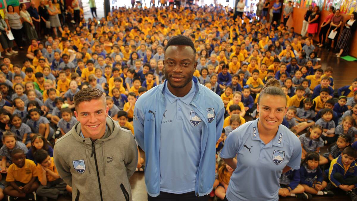 Taking over: Charles Lokolingoy (centre) with Sydney FC club mates Cameron Devlin and Chloe Logarzo at Carlton South Public School on Monday. Picture: John Veage