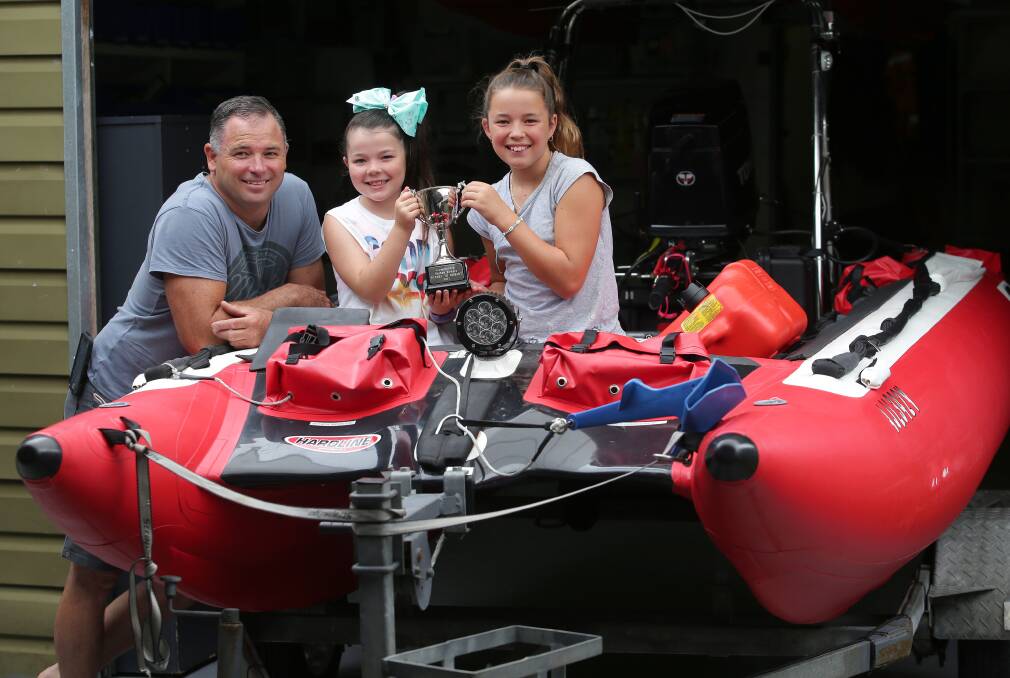Inflatable: Nathan Rykers alongside his two daughters Jesse, 8, and Maddy, 11, (holding a trophy they made for him) and his trusty inflatable boat. Picture: John Veage