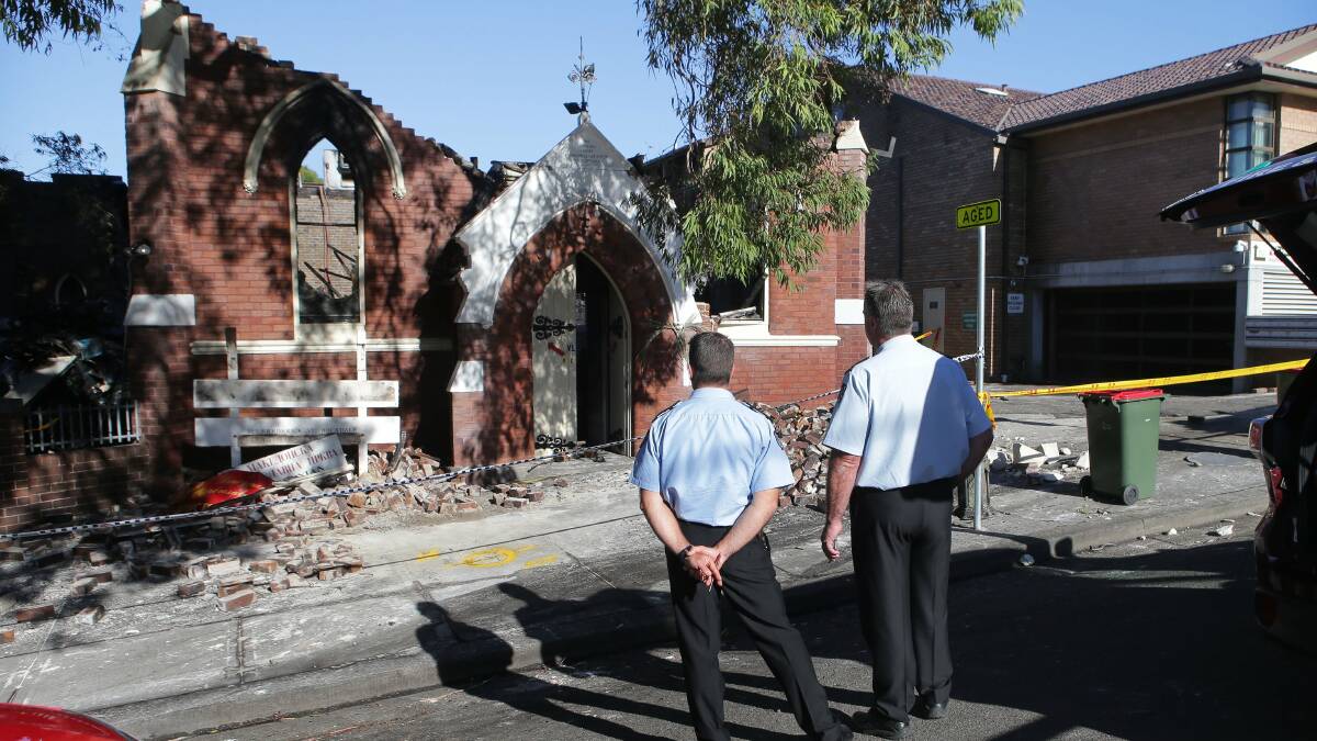 Destroyed: Investigators look over the scene after a fire destroyed a Rockdale church. Picture: John Veage