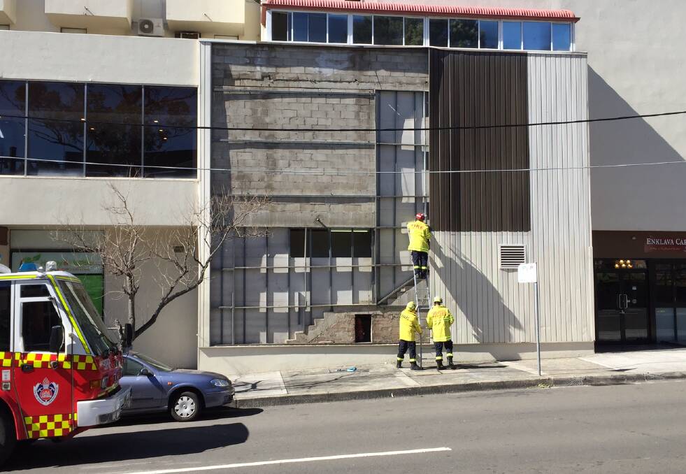 Emergency response: Firefighters secure a building at Miranda after wind stripped panelling off the facade. Picture: John Veage