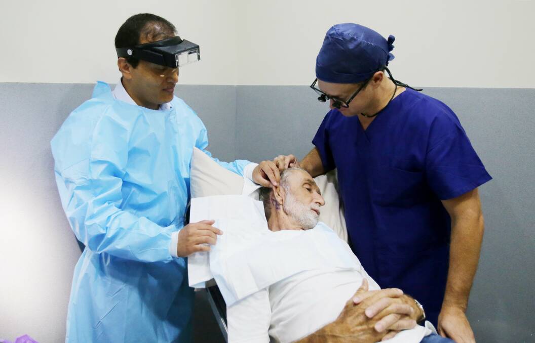 In-training: Dermatologist and skin cancer specialist Saleem Loghdey teams up with cosmetic, plastic and reconstructive surgeon Louis Wessels, to assist patient George Valiukas. Picture: Chris Lane