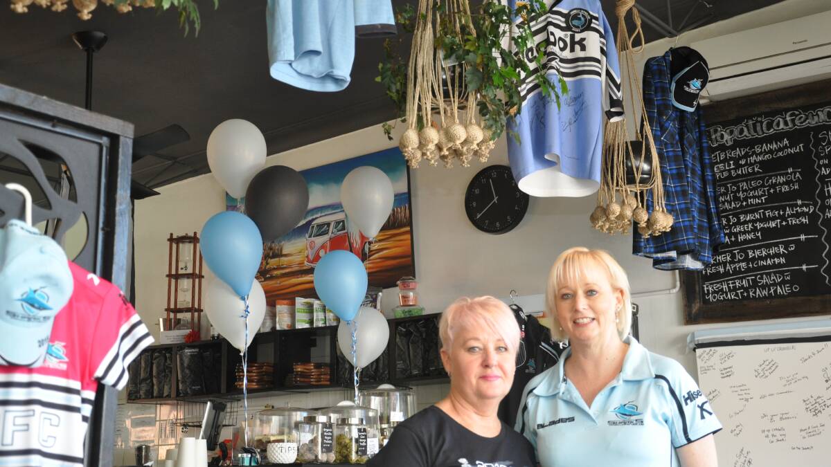 Annette Roberts and Karen Hook at Popati Cafe with historic Sharks jumpers and flannelette shirt hanging above.