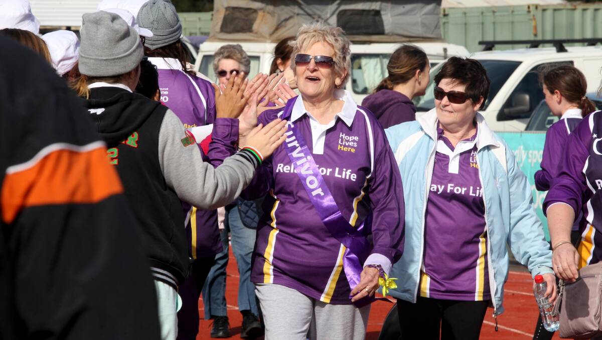 Survivors and carers receive high-fives from participants at the end of the Sutherland Shire Relay for Life in 2014.