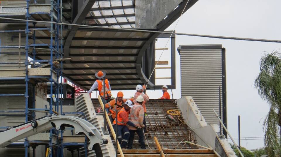 Walk this way: Workers guide a section of the walkway into place as it is lowered by a crane. Picture: Robin Robertson