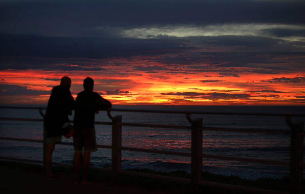 Bright start, gloomy finish expected: Early morning walkers were treated to a colourful Sydney sunrise at Nth Cronulla beach after a week of wet weather. Picture: John Veage