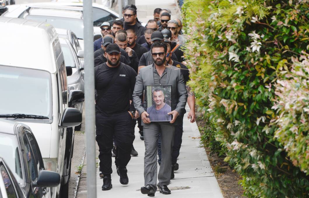 A man holding a picture of Mick Hawi against his chest leads a silent entourage into the mosque. Picture: Nick Moir