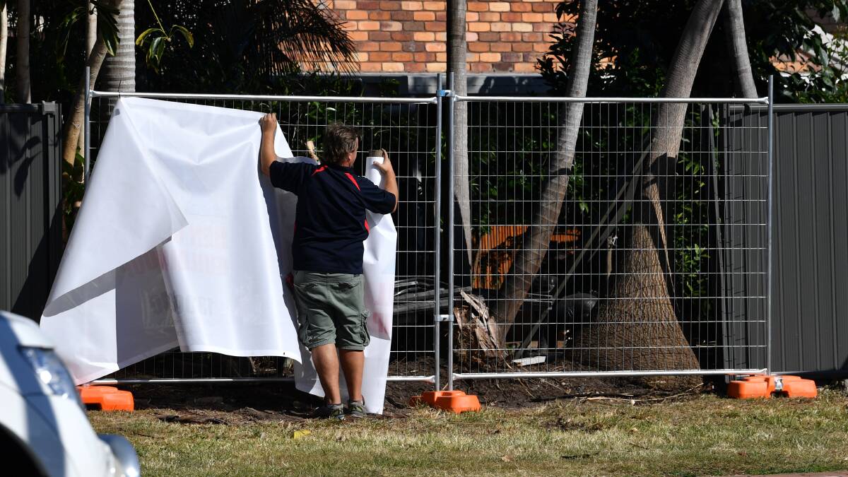 A man is seen putting a screen up at the location where former Ironman champion Dean Mercer died at Markeri Street, Mermaid Waters on the Gold Coast. Photo: AAP