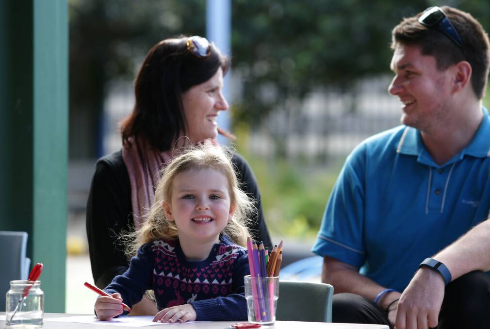 Ready to go: Chloe Simpson, 4, prepares for school at Allison Crescent Early Education Centre at Menai, while mum Carly and educator Brendon Eady look on. Picture: John Veage
