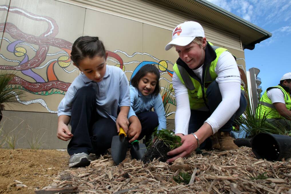 Green vision: The Discovery Point community and pupils Soukana Hijazi and Navya Jain, with Stefanie Hicks from Australand, teamed up for Schools Tree Day on Friday. Picture: Jane Dyson