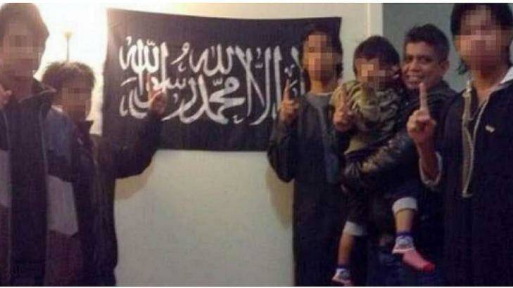 A photo Zulfikar Shariff posted on his Facebook page of himself with his children in front of a flag used by jihadi terror group Photo: Supplied