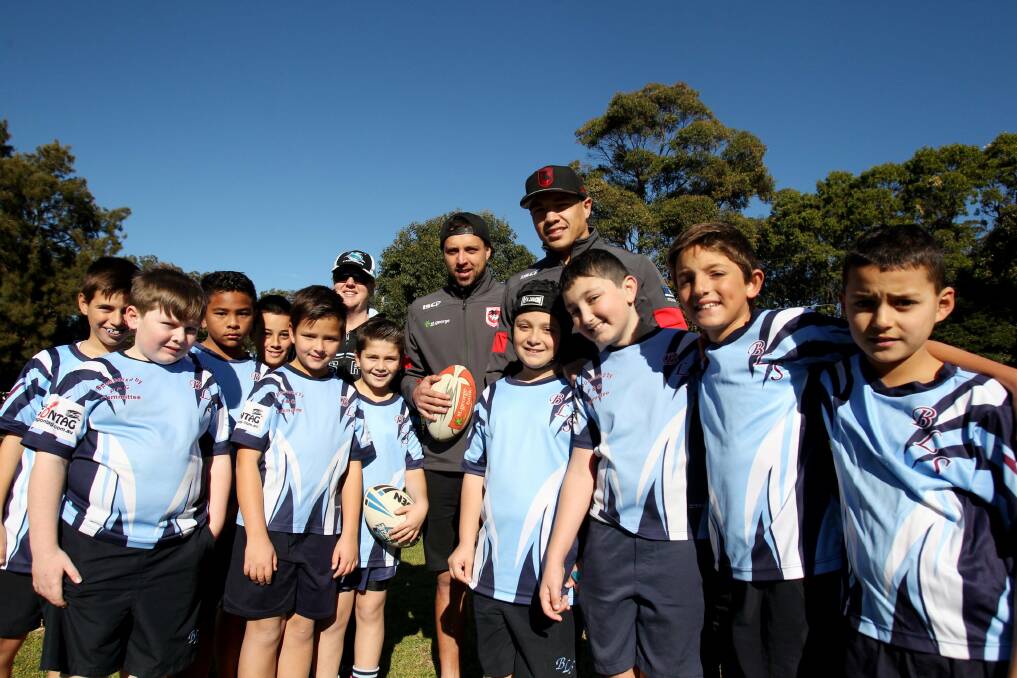 We love our footy: Brighton-Le-Sands Public School teacher Julie Bernhardt (left, back),  Dragons players Gerard Beale and Tyson Frizell, and the students at Carss Park on Friday. Picture: Chris Lane