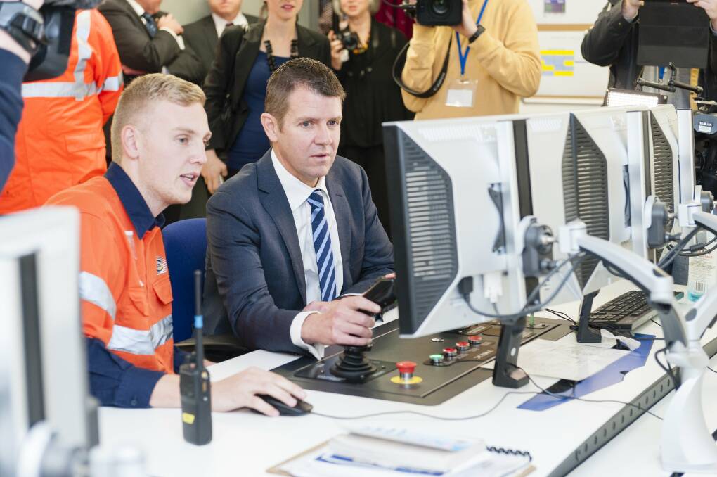 Hands on: Riley Baker shows Premier Mike Baird the remote controls of the automated stacking cranes.

