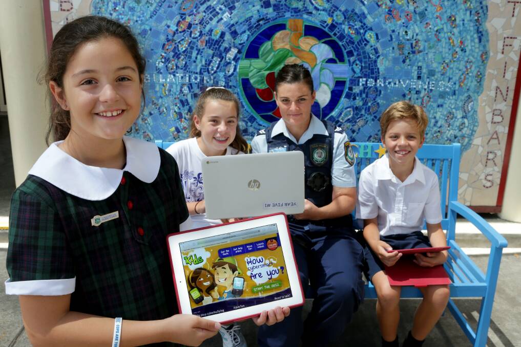 Practical knowledge: St Finbar's Primary School pupils Scarlett Ianni, Abbey Djundja and Oliver Davis get smart with the cyber world with the help of Senior Constable Carmen Farrell. Picture: Jane Dyson