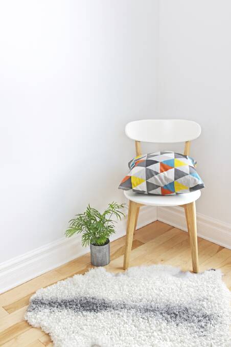 Home decor. Chair with bright cushion, plant and sheepskin rug on the floor. nest