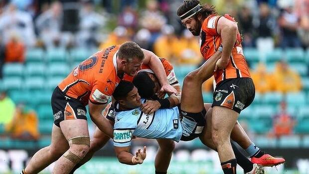 Crunch time: Cronulla's Ricky Leutele about to hit the turf as the Tigers' Matt Lodge and Aaron Woods take control. Photo: Getty Images.
