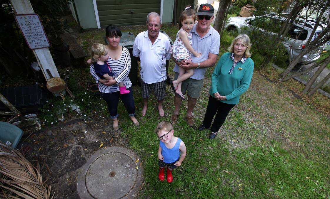 Piping up: Grafton Street residents have suffered a burst sewage pipe five times in the past seven weeks and are demanding Sydney Water take action. (From left) Rebecca Grant with daughter Gwen, 2, son Finn, 4, her father Kevin Grant, Howard Wright with granddaughter Emily and Verlie Stevenson. Picture: John Veage
