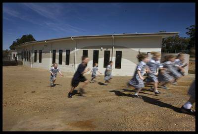 Photograph Simon O Dwyer. The Sunday Age Newspaper. 260310. Photograph Shows. School children from Emmaus Catholic primary School at Mt Clear near Ballarat make a run for home on the last day of school for the term. In the background is a new multi purpose building designed and constructed in a matter of months under the BER stimulus funding. 