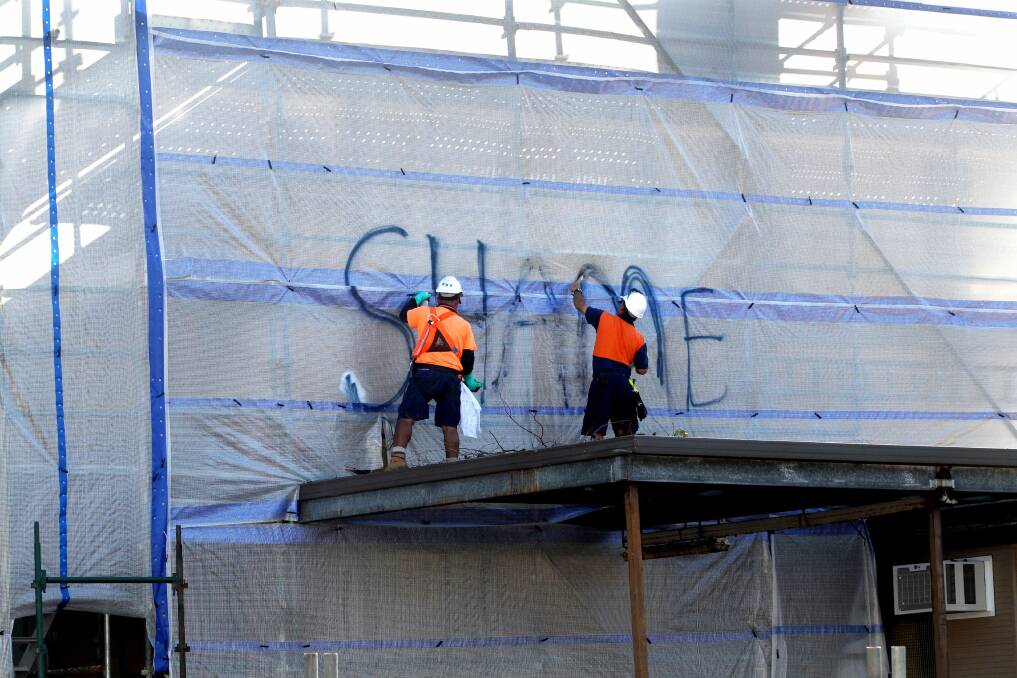 Clean up: Workmen remove the graffiti from Griffith House this morning. Picture: Jane Dyson