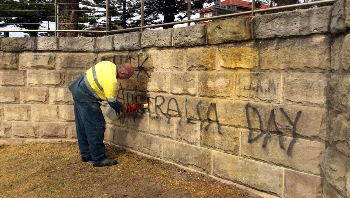 Very sad: Contractor Sam Bennett gets to work on the graffiti. 