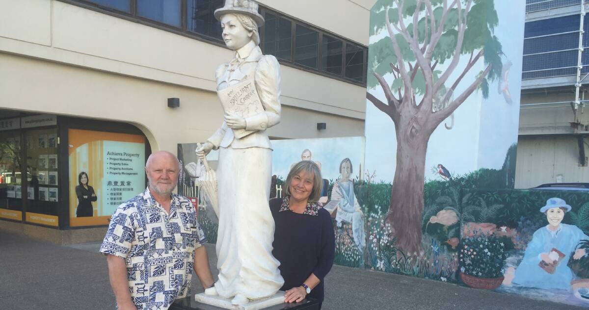 Carve her name with pride: Sculptor Jacek Luszczyk and community artist Gerti Stewart with the Miles Franklin statue in Hurstville in front of the mural depicting scenes from Franklin's life.