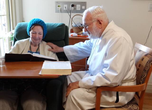 Continuing fellowship: Dr Douglas Golding reads to Fay Burgess, 87, at Blakehurst Aged Care.