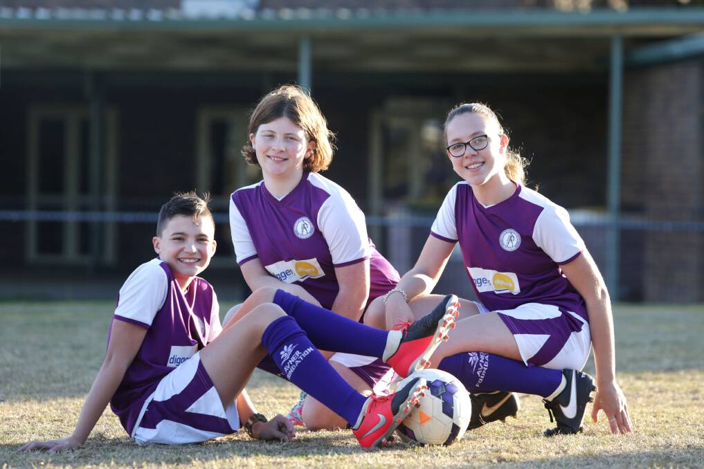 Cancer support: Sutherland Shire players Ben,Kirra and Lilly from Gwawley Bay FC already play in purple so changing socks was an easy job. Picture: John Veage