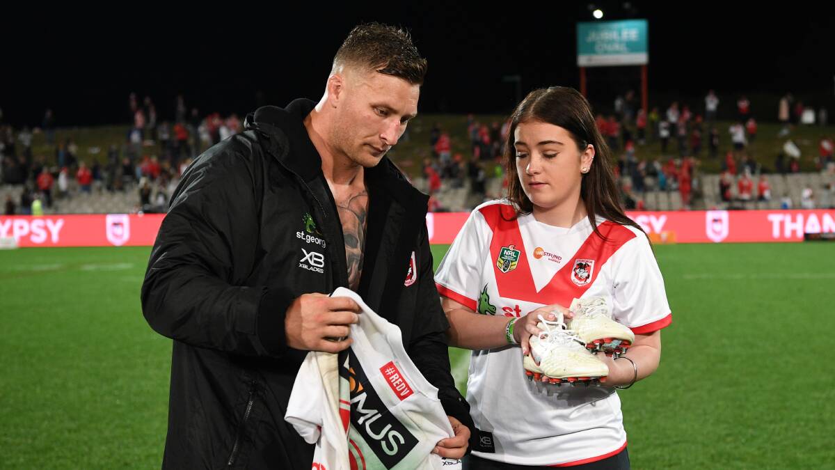 Gesture: Dragons forward Tariq Sims presents Lance Thompson's daughter, Shalisse, with his number 12 jersey and boots on Sunday. Picture: AAP Image
