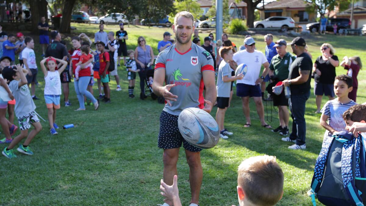 Back to juniors: Dragons winger and Renown United junior Jason Nightingale passes the footy with a young fan. Picture: John Veage
