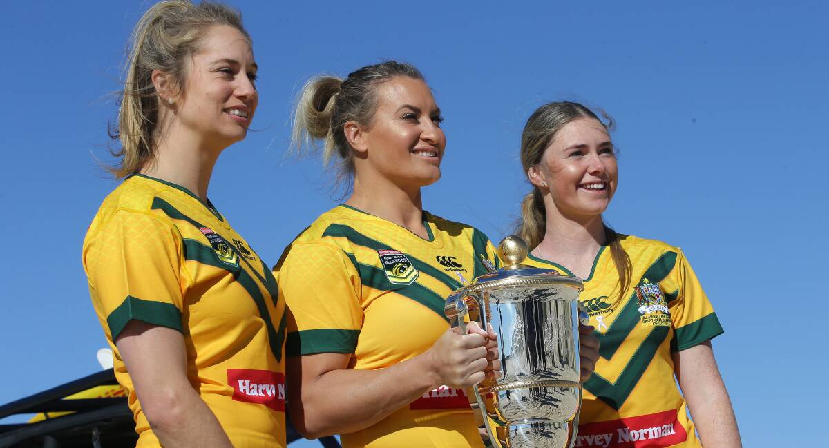 Golden girls: Cronulla Sharks star Ruan Sims (centre), Kezie Apps (left) and shire local Maddie Studdon with the World Cup trophy at Wanda Beach. Picture: John Veage