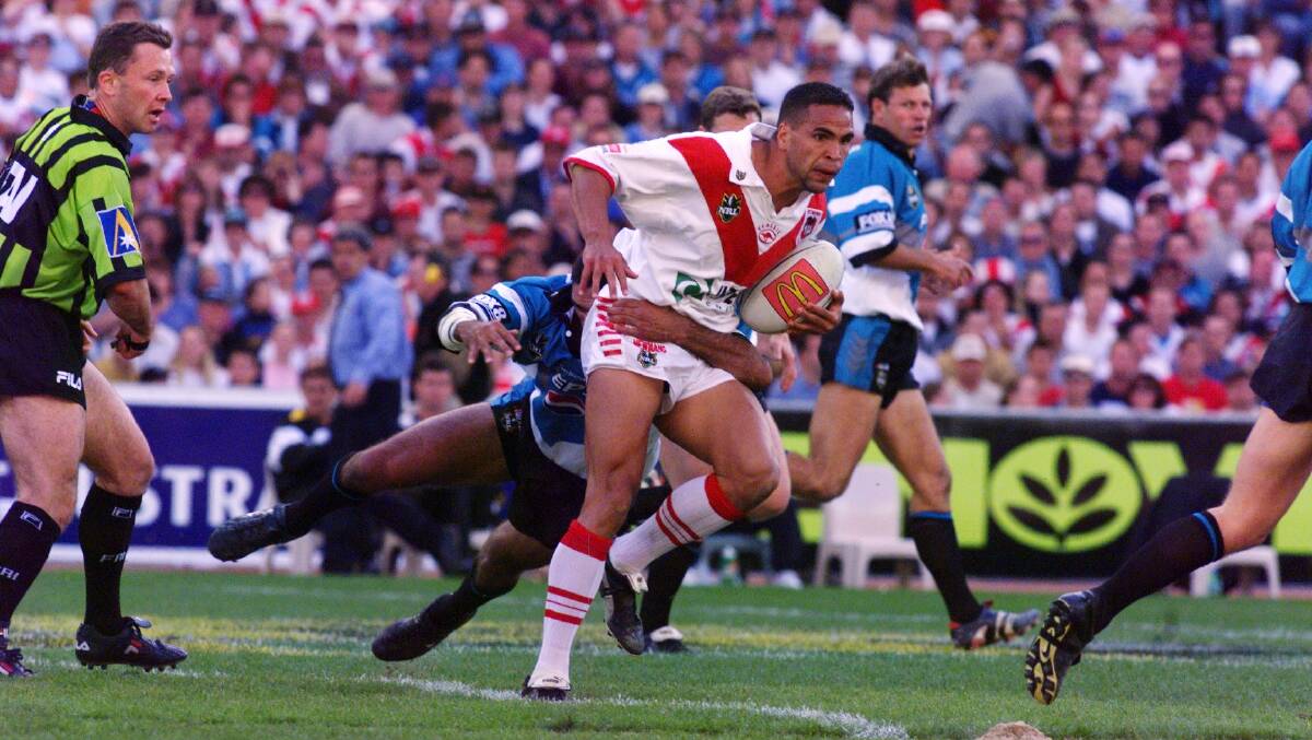 Rivalry: Anthony Mundine runs the ball for the Dragons as Sharks legend Andrew Ettingshausen looks on. Picture: Ken Robertson