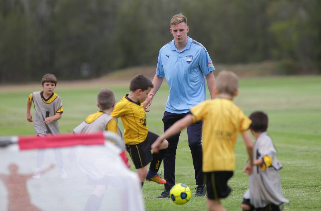Footy: Sydney FC players came down to Oyster Bay for a kick around with a bunch of young footballers. Pictured is Aaron Calver with the children. Picture: John Veage