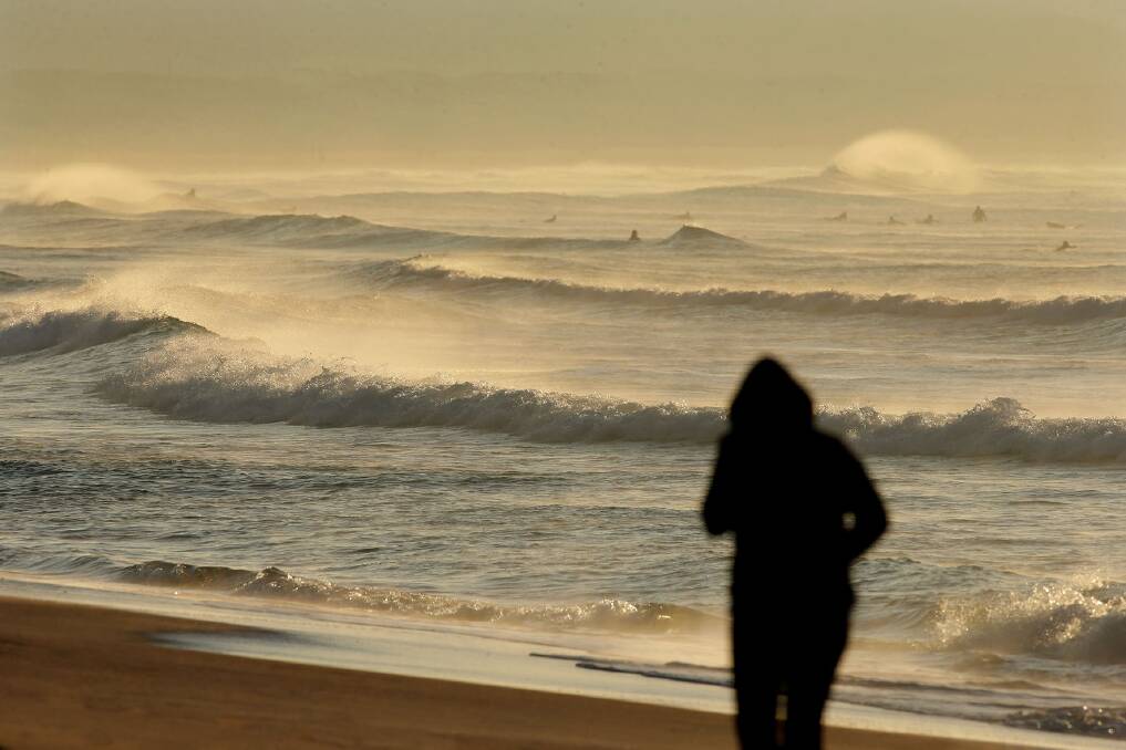 A swell stroll: A rugged-up jogger at Cronulla on Monday. Picture: John Veage