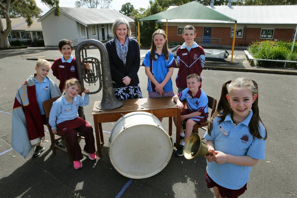Ringing in the 90th year: Engadine Public School pupils Oliver, Felicity, Charlie, Ruby, Leo, Ryder and Addison with principal Sara Swift, with an original school timber desk, bell and musical instruments from the early day of learning. Picture: John Veage