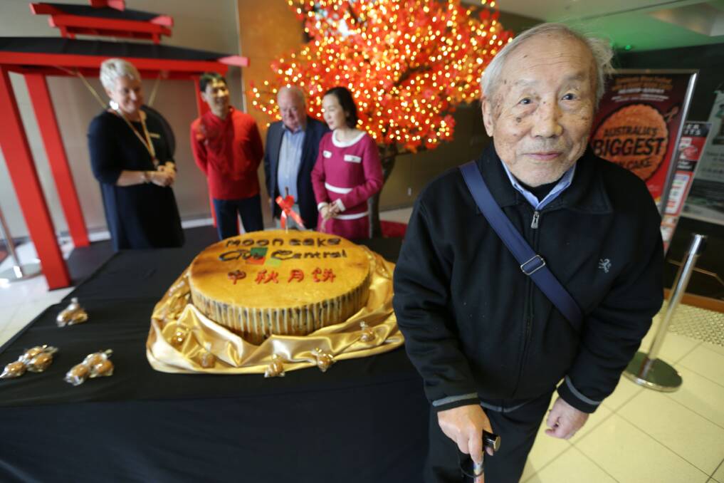 Festive cake: A customer waits for his cut as Westfield Hurstville centre manager Michelle Fragias, Bakery King owner Michael Cheung, Club Central president Brian Cloney, and Georges River councillor Nancy Liu prepare to measure the creation. Picture: John Veage