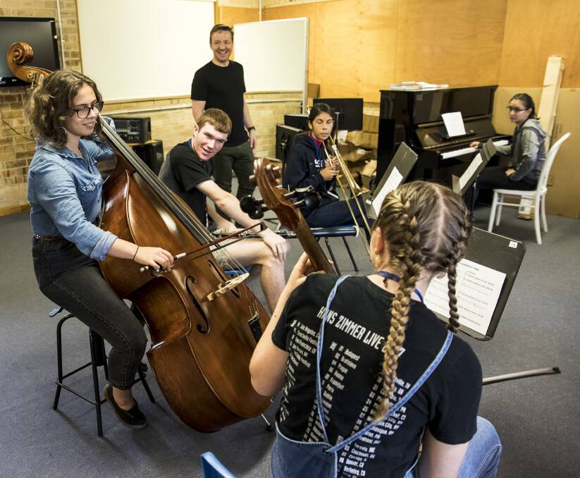 Musical workshop: St George Girls High School student Zoe Morris on the double bass, with international composer Paul Rissman and fellow students watching on.
