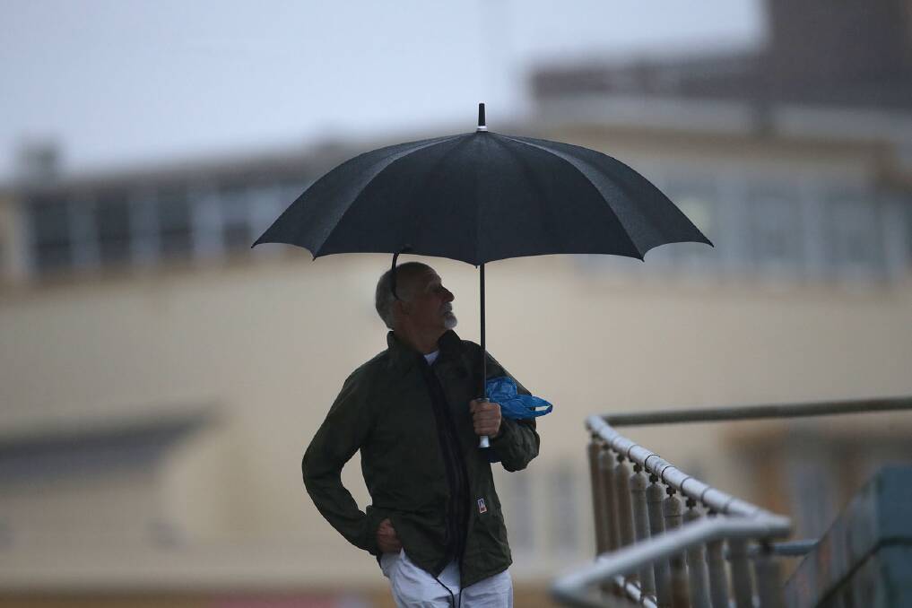 Rainy stroll: An early beach walker enjoys a cooler morning on Wednesday. Picture: John Veage