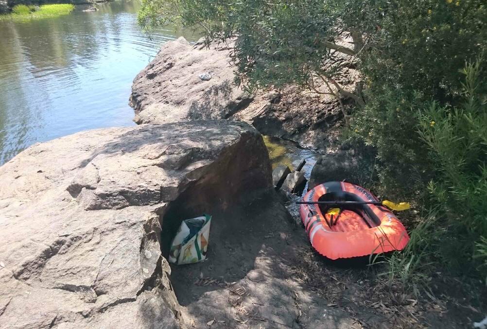 An inflatable boat and a bag were left by the water's edge.