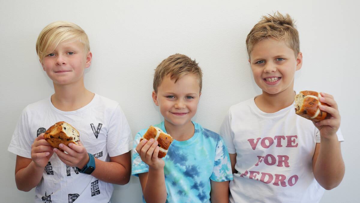 Butter me up: The Bartlett brothers Beau, 11, Kobe, 7, and Hunter, 9, of Lilli Pilli, dig into some hot cross buns. Coles hot cross buns are big sellers in the shire. Picture: Chris Lane
