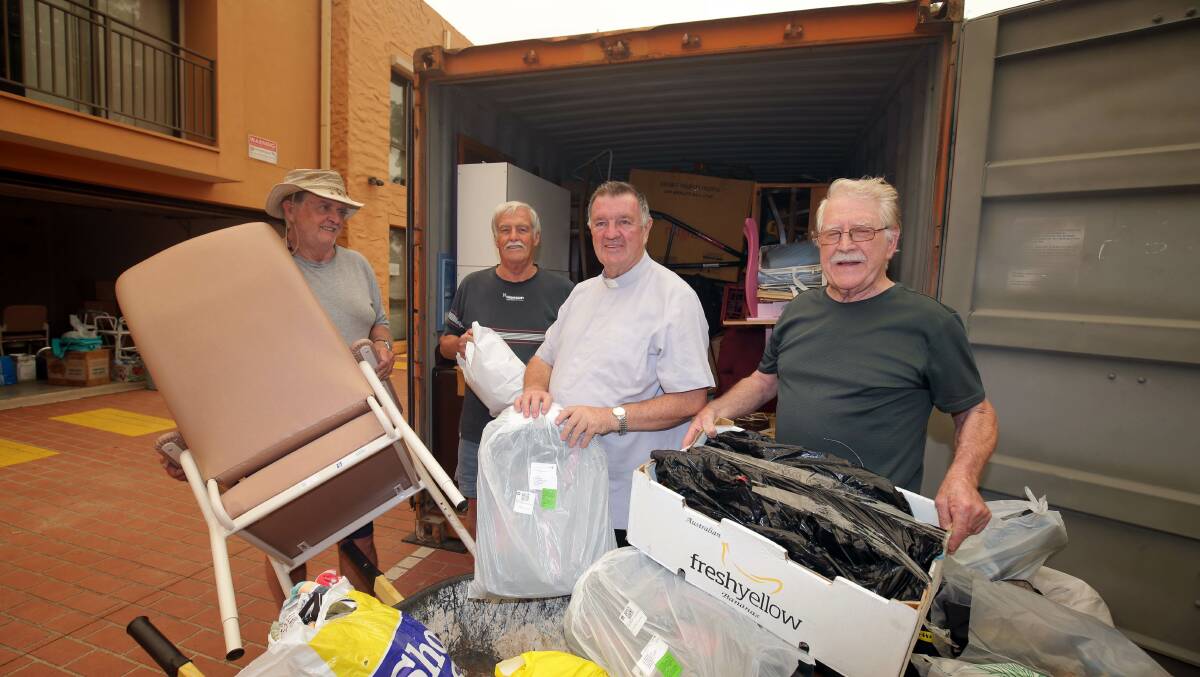 Goodwill gesture: Barry Elliott, Bernie Brennan, Monsignor Brian Rayner and Peter McGrath load goods into a container. Picture: Chris Lane