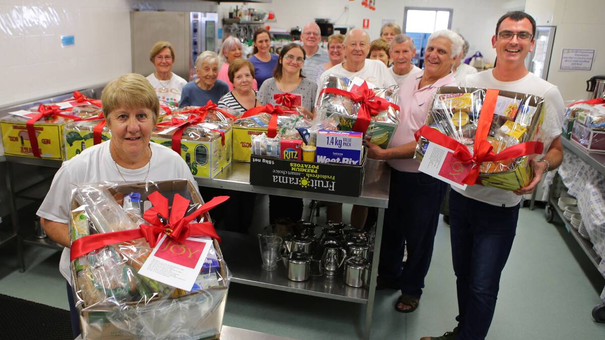Festive bounty: Pastor Brian Summers, right, with volunteers at Caringbah Baptist Church finishing off their Christmas hampers for needy families in the shire. Picture: John Veage