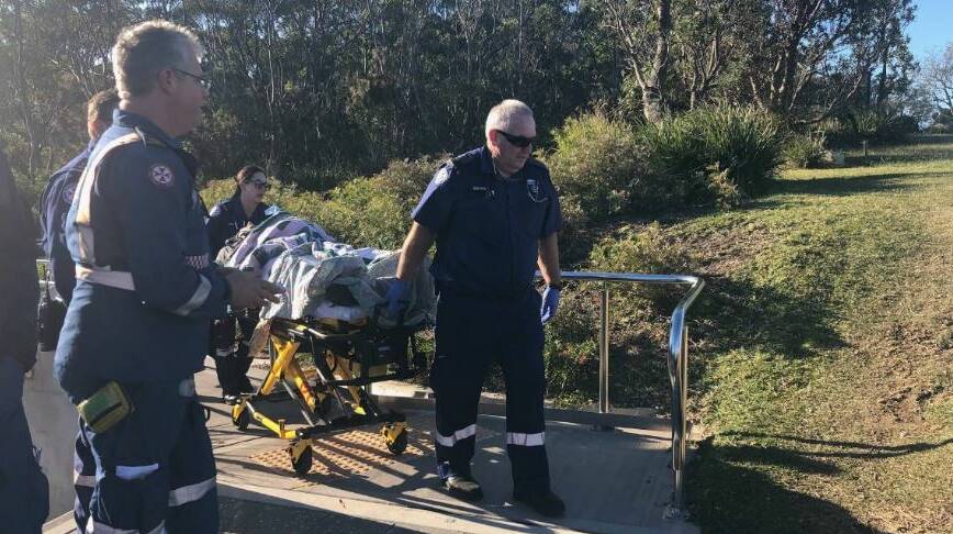 Paramedics wheel the injured hang glider pilot to a rescue helicopter. 