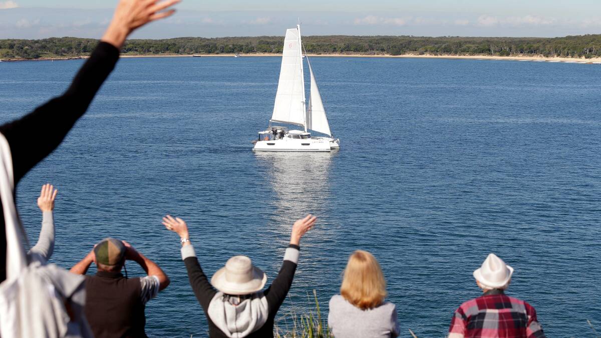 Gordon and Louise Coates are welocmed by family and friends as they sail their catamaran past Bass and Flinders Point into Port Hacking. Picture Chris Lane