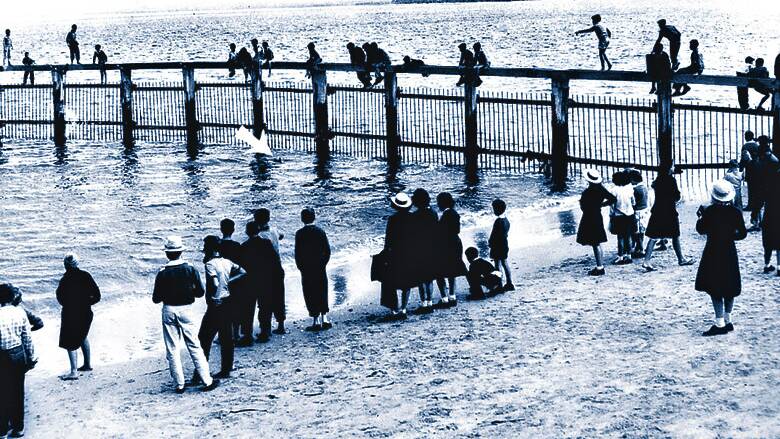 1960 - Spectators try to catch a glimpse of the shark (arrowed) in the baths.
