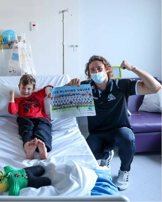 Nicho Hynes with a young patient in hospital as part of the Sharks Have Heart program. Picture supplied